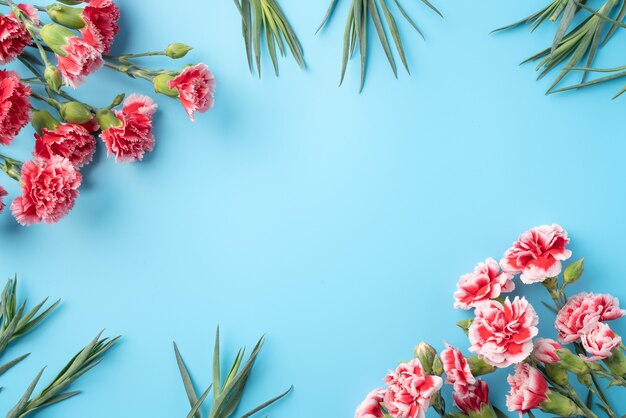 밝은 파란색 테이블 표면에 카네이션 꽃다발과 어머니의 날 휴일 인사말 선물 디자인의 개념