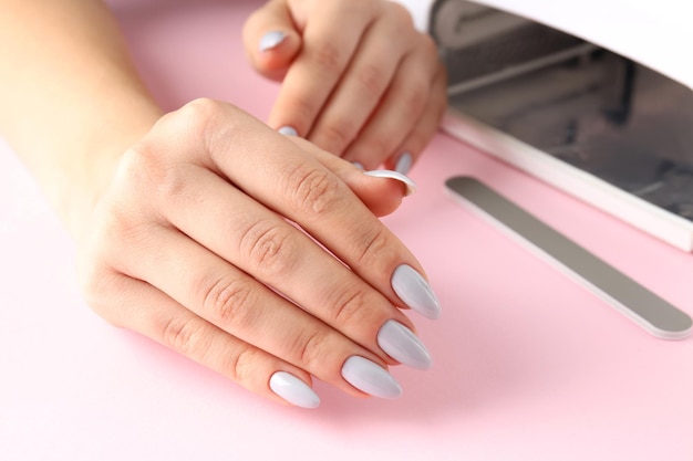 Concept of nail care with female hands on pink background