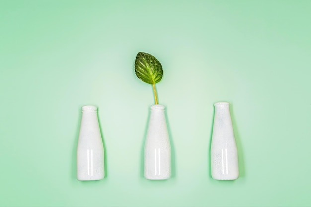 Concept of natural cosmetic with bottles and leaf on light green background