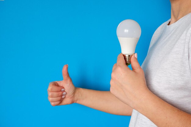 Concept of new idea and innovation with light bulbs LED lamp in female hands on a blue background