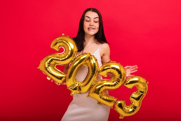 The concept of the New Year and Christmas A young attractive woman in a stylish dress holds the numbers 2023