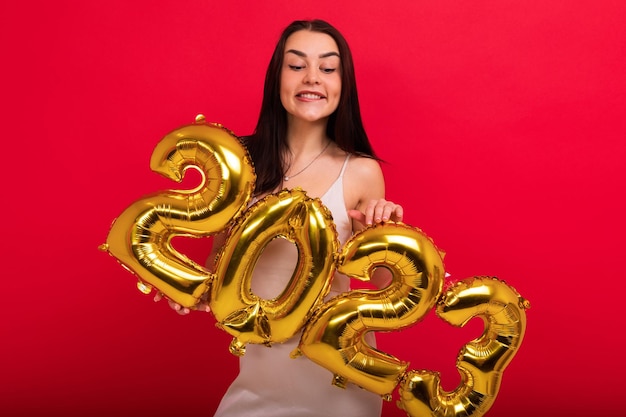 The concept of the New Year and Christmas A young attractive woman in a stylish dress holds the numbers 2023