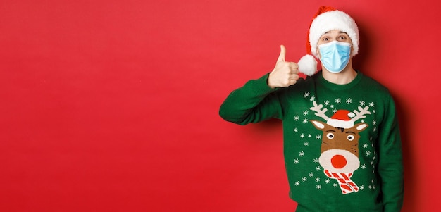 Il concetto di nuovo anno covid e distanziamento sociale ha stupito il giovane ragazzo che celebra il natale indossando medic...