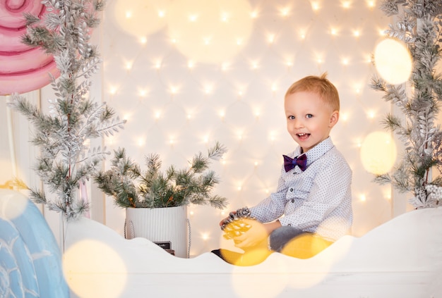 The concept of new year holidays. Happy toddler boy on background of Christmas lights. 