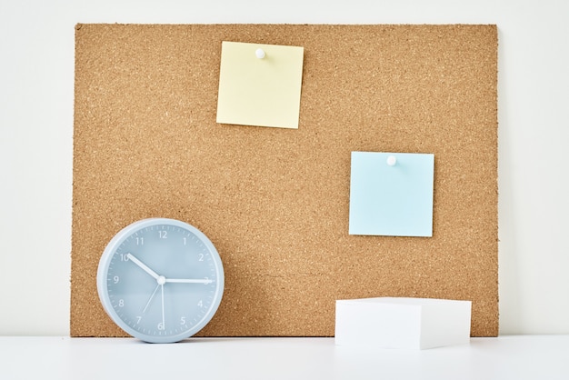 Concept of notes, goals, memo or action plan. Sticky notes on a cork board and alarm clock  in workplace office or home