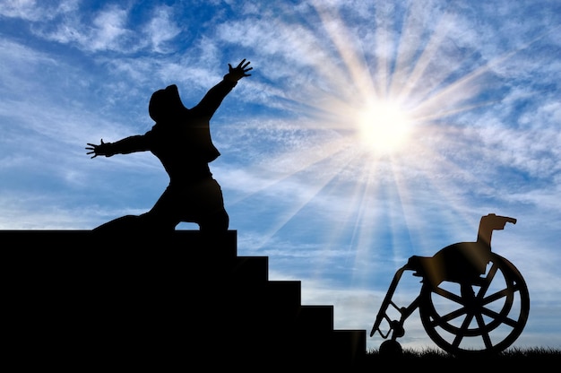 障害とポジティブの概念。昼間の階段のてっぺんで幸せを体験する障害者のシルエット