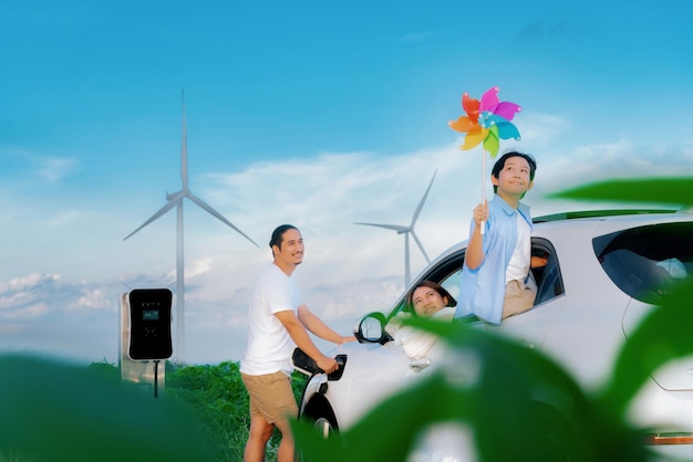 사진 전기 자동차가 있는 풍력 터빈에서 진보적인 행복한 가족의 개념