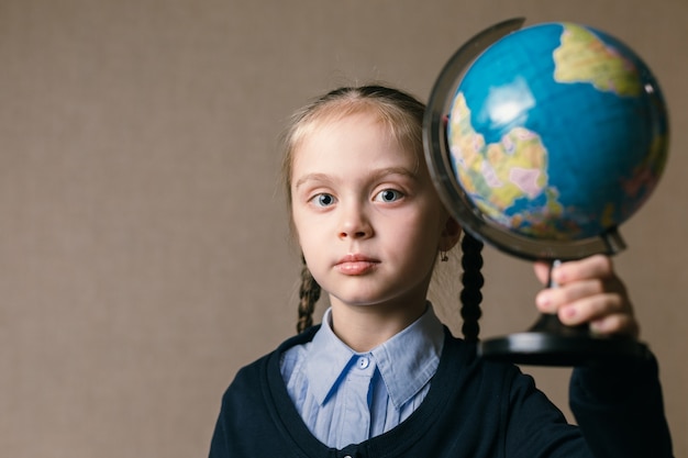 Concept - onderwijs. Kaukasisch meisje dat een bol houdt