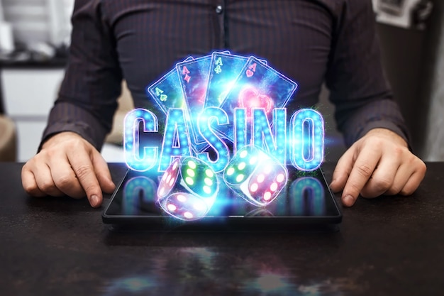 オンラインカジノ、ギャンブル、オンラインマネーゲーム、賭けのコンセプト。ネオンカジノチップ、カジノの碑文、ポーカーカード、サイコロがラップトップから飛び出します。