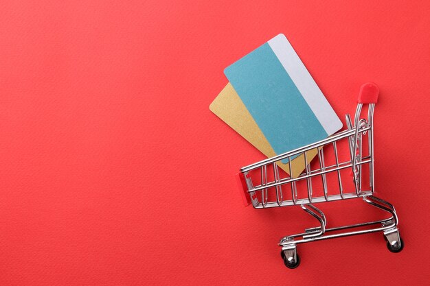 The concept of online shopping. Composition with discount cards and shopping trolley on a red background