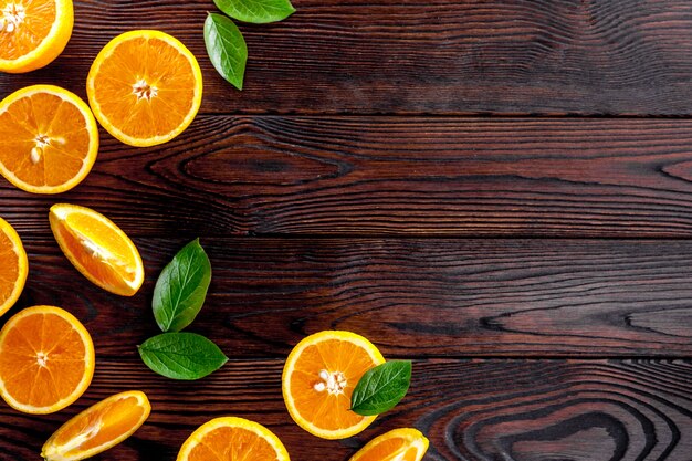 Concept of orange slices with leaves on dark wooden