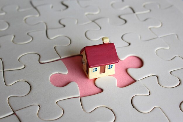 Concept of owning a home or completing a home purchase Toy house and missing puzzle pieces