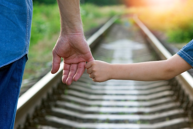 Concept parent holds the hand of a small child and railroad on future