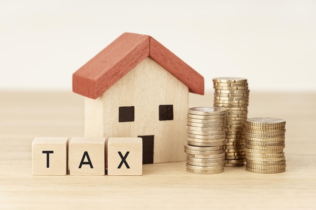 Concept of paying tax for housing and property House model money and wooden blocks with text