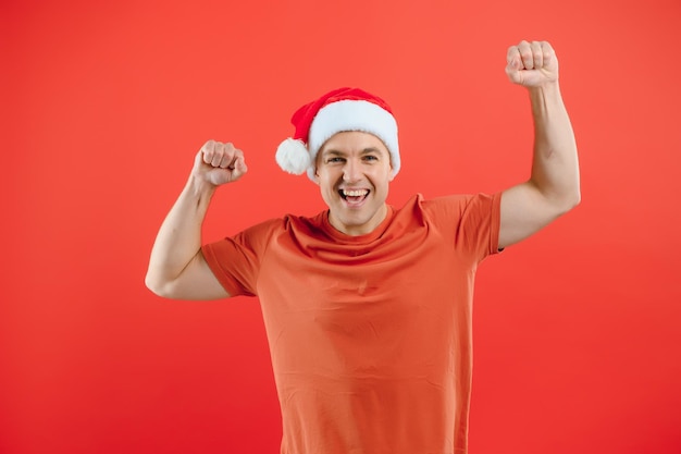 Концептуальные люди, язык тела, одобрение, рекомендательный возбужденный мужчина в шляпе Санта-Клауса, изолированной на красном студийном фоне с пространством для текста