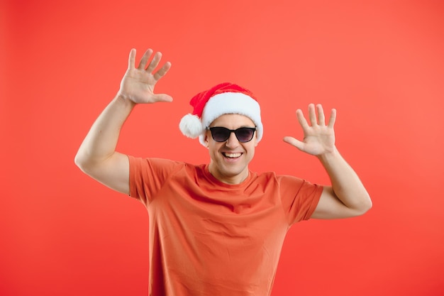 Concept people, body language, approval, recommendationan excited man Santa Claus hat isolated on red studio background with space for text