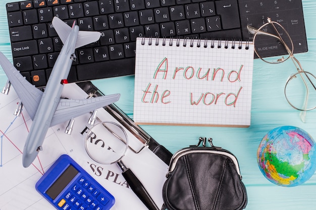 Concept of planning vacation - airplane, globe, wallet. Around the world written on the notepad.