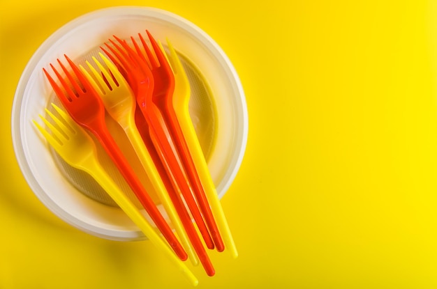 Concept plastic utensils on a yellow background with copy space