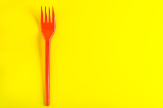 Concept plastic utensils on a yellow background with copy space
