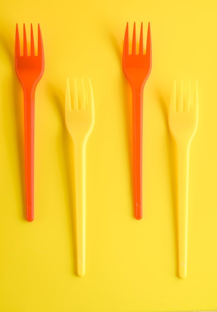 Концепция пластиковой посуды на желтом фоне