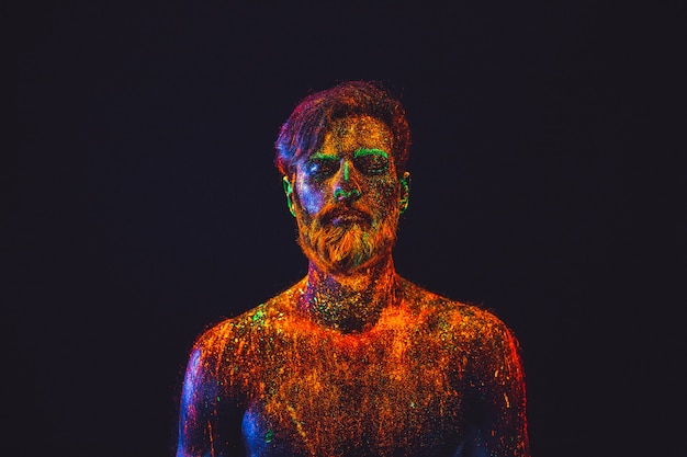 Concept. Portrait of a bearded man. The man is painted in ultraviolet powder.