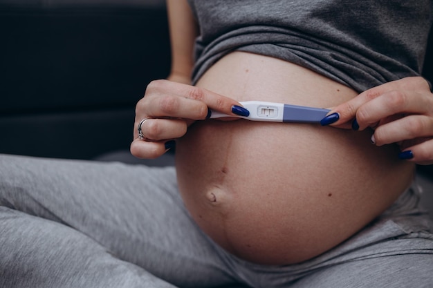 The concept of a pregnant woman holding a pregnancy test and remembering how she first learned about pregnancy