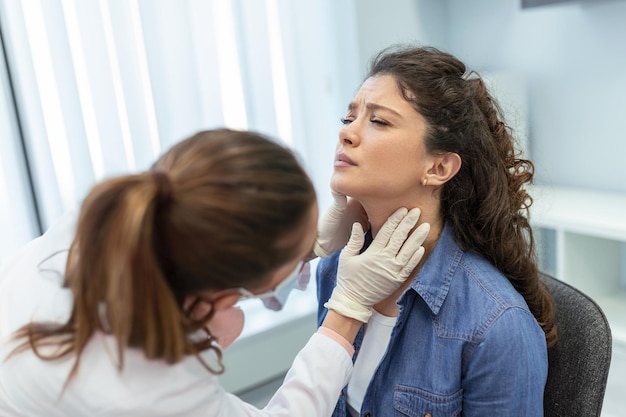 Concept of professional consultation in therapist system Close up portrait of doctor woman examining tonsils of young lady in medical office