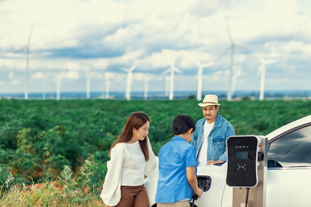 Concept progressieve gelukkige familie bij windmolenpark met elektrisch voertuig