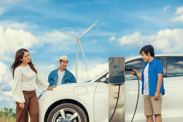 Concept progressieve gelukkige familie bij windmolenpark met elektrisch voertuig