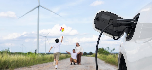 Concept progressieve gelukkige familie bij windturbine met elektrisch voertuig