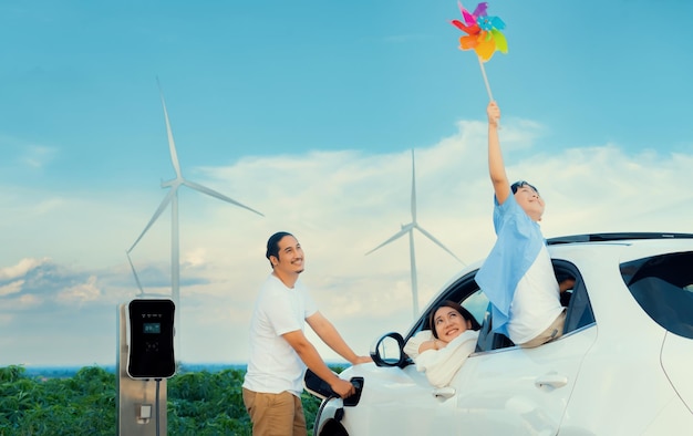 Concept progressieve gelukkige familie bij windturbine met elektrisch voertuig