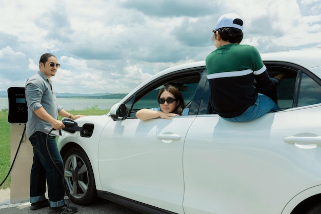 Concept of progressive happy family at green field lake with electric vehicle