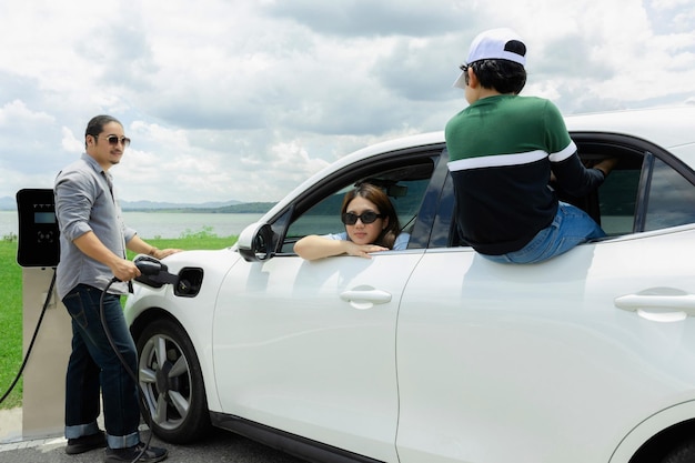 Concept of progressive happy family at green field lake with electric vehicle