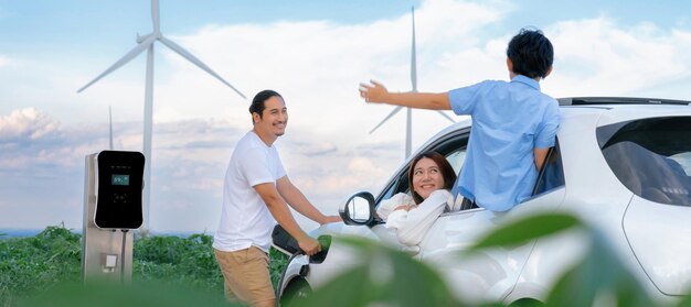 Concept of progressive happy family at wind farm with electric vehicle