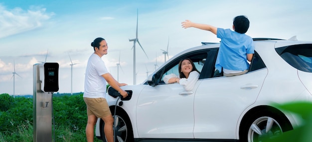 Concept of progressive happy family at wind farm with electric vehicle