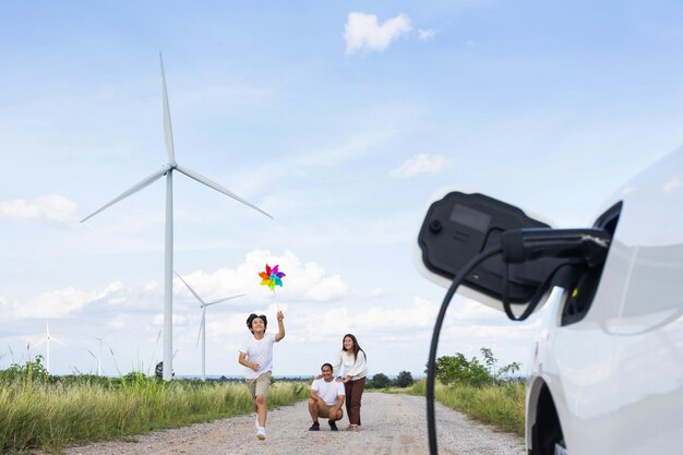 Concept of progressive happy family at wind turbine with electric vehicle