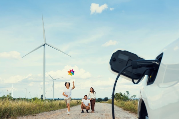 전기 자동차가 있는 풍력 터빈에서 진보적인 행복한 가족의 개념