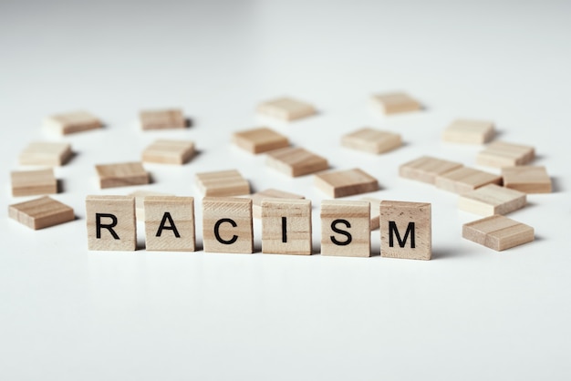 人種差別の概念と人々の間の誤解、偏見、差別。白い背景に人種差別という言葉で木製のブロック