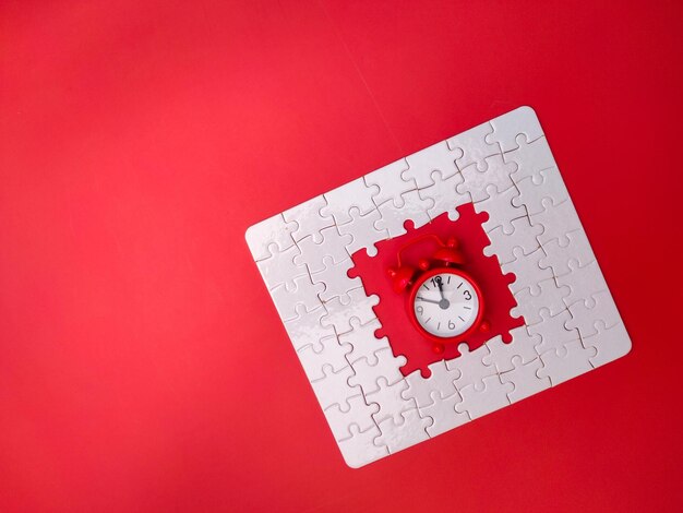 Concept red alarm clock and puzzle on red background