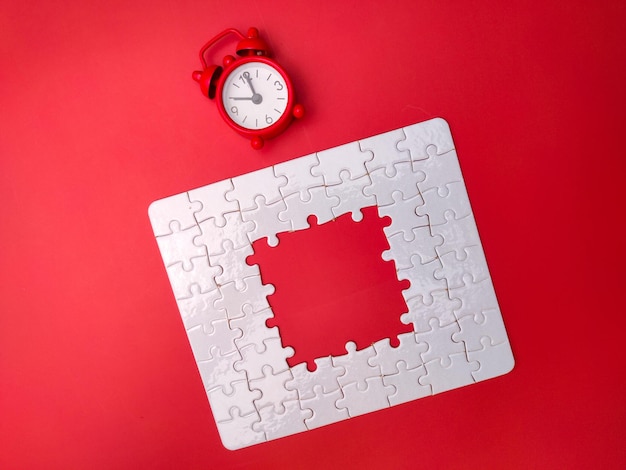 Concept red alarm clock and puzzle on red background