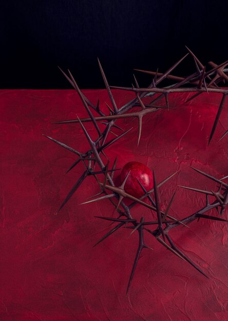 Фото Концепция красного пасхального фона с терновой короной и окрашенным яйцом вертикальное изображение