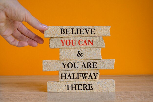 Concept red words Believe you can and you are halfway there on brick blocks