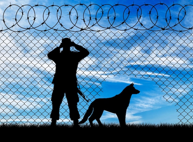 Concept of the refugees. Silhouette of a border guard and a dog near the hole in the fence