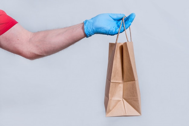 The concept of safe delivery in close-up. the courier's hand in protective medical gloves holds a paper bag. contactless delivery of orders