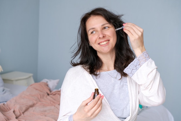 Concept schoonheid en huidverzorging Het gezicht van de vrouw past tea tree gezichtsserum toe