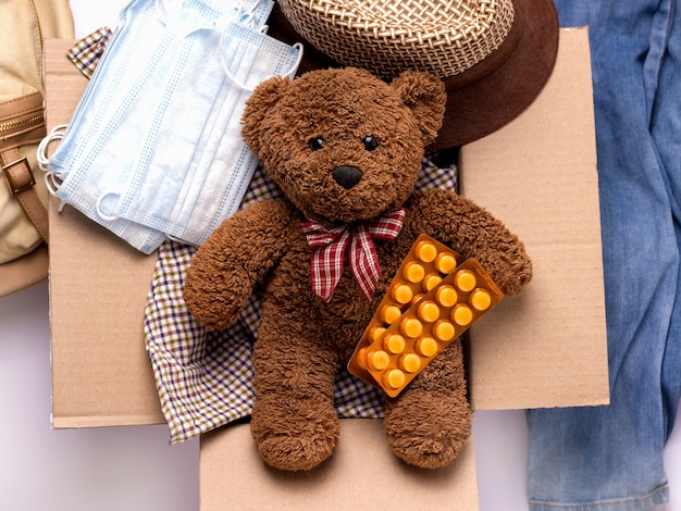 The concept of sending care, donations. In the box are vitamins, things, masks and a teddy bear
