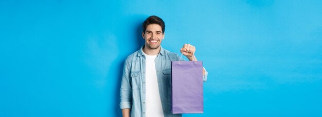 Concept of shopping holidays and lifestyle young handsome man holding paper bag with present and person