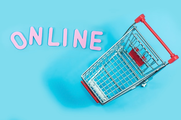 Concetto di shopping online con carrello sul blu per lo sfondo