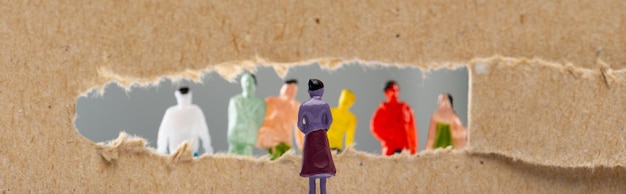 Photo concept of social rights with people figures near hole in cardboard isolated on grey panoramic shot