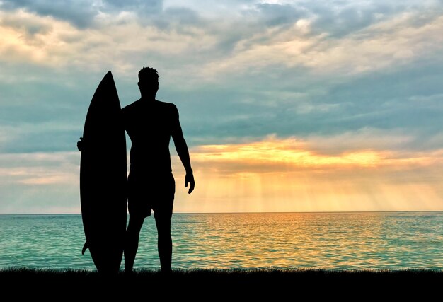 スポーツの概念。夕方の海に対してサーファーのシルエット